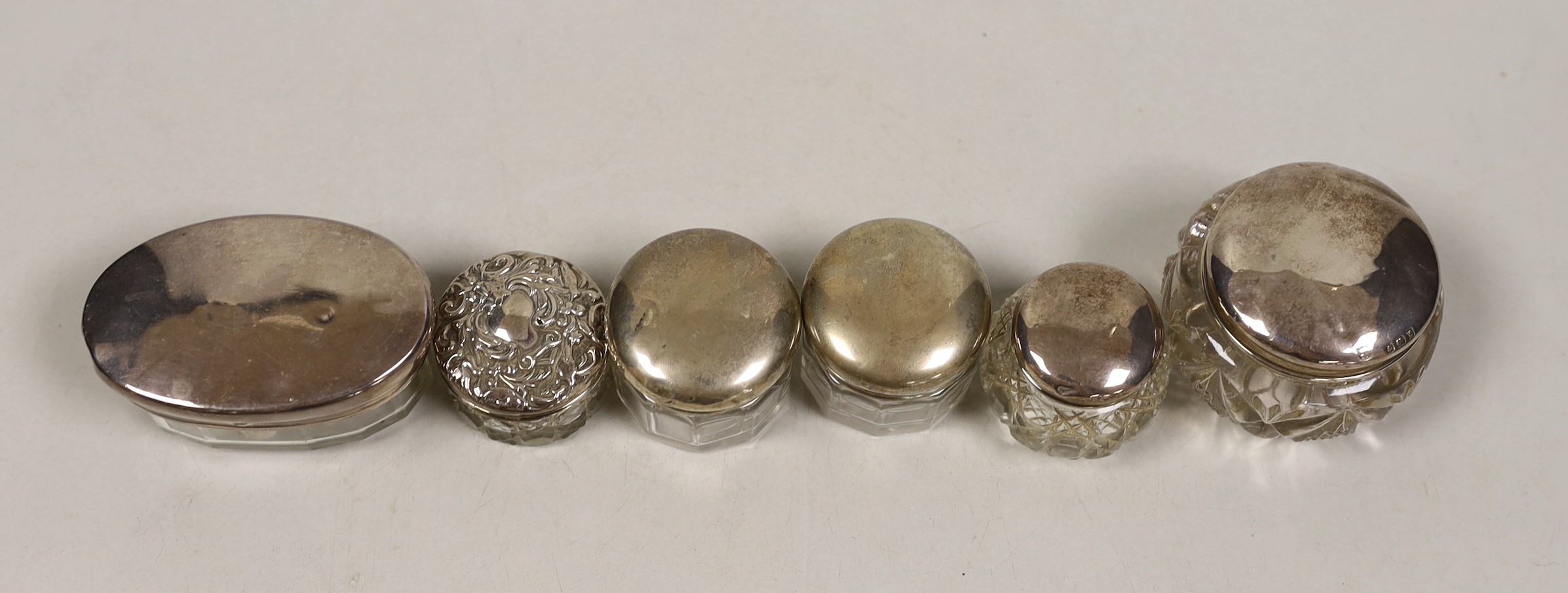 Six assorted small silver mounted glass toilet jars.